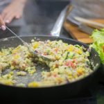 Fresh vegetable stir-fry in a pan with lettuce salad, captured in a kitchen setting.