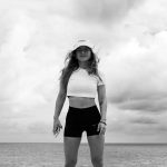 Black and white portrait of a woman on a beach in Natal, Brazil with dramatic clouds.